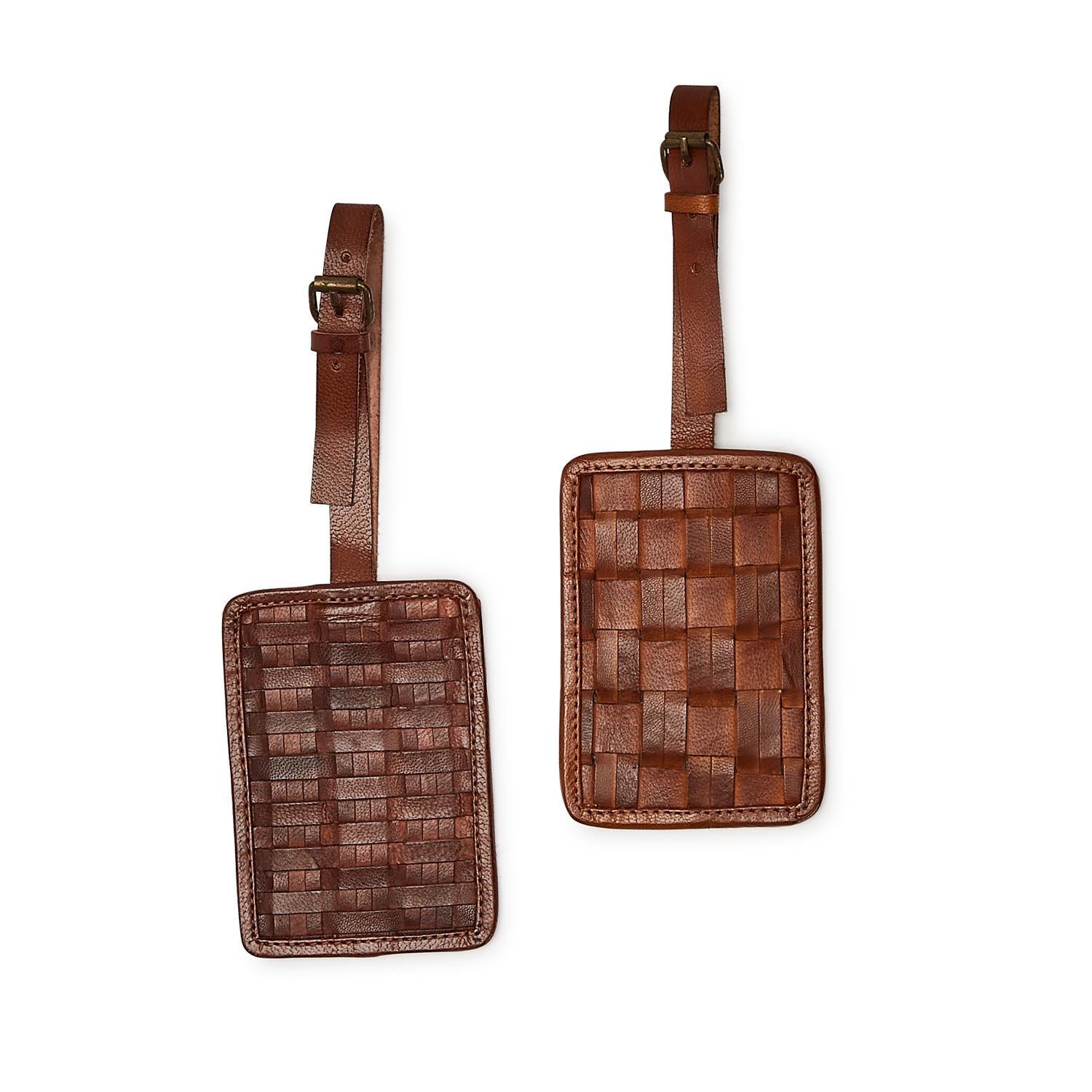 Two brown woven leather luggage tags on a white background